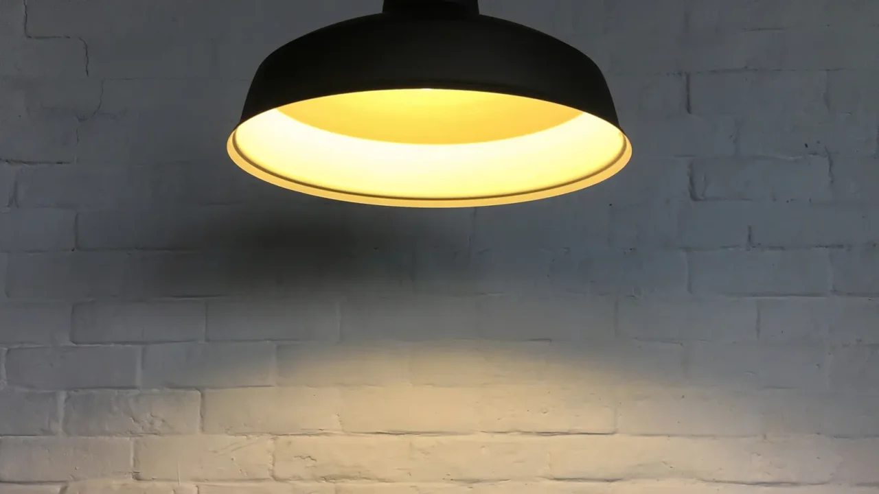 Black fixture of lamp hanging on ceiling and have white bricks wall is background for interior decoration design.