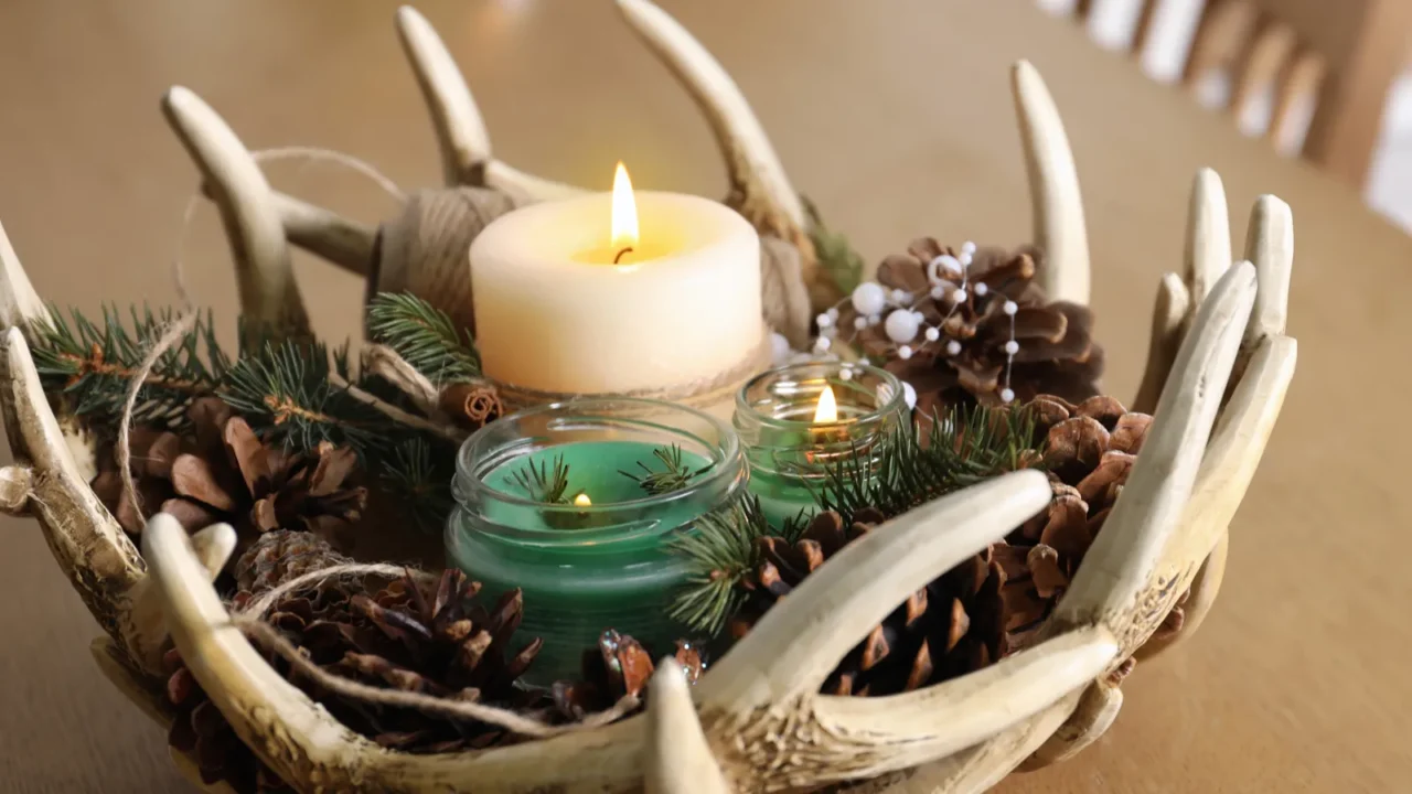 Burning scented conifer candles with Christmas decor on wooden table indoors