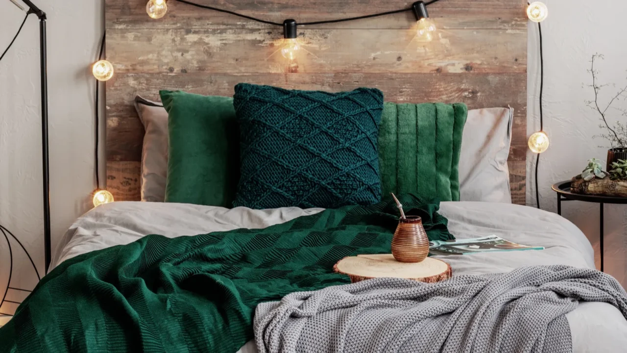 Emerald green and grey bedding on double bed with wooden headboard