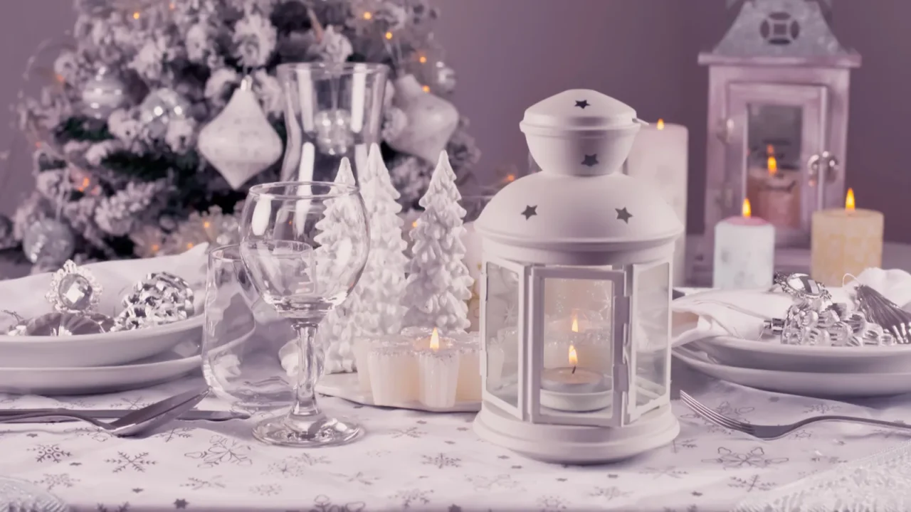 Festive Christmas table place setting with silverware, candles and decorated Christmas tree