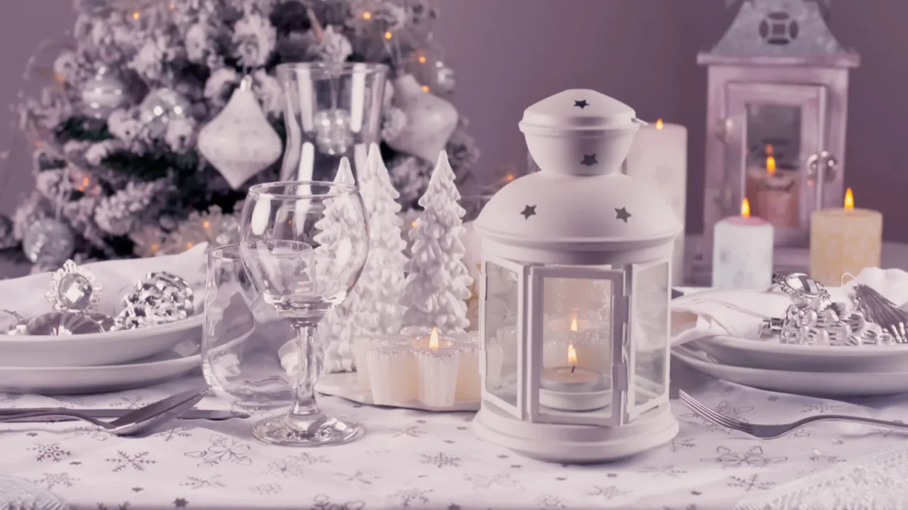 Festive Christmas table place setting with silverware, candles and decorated Christmas tree