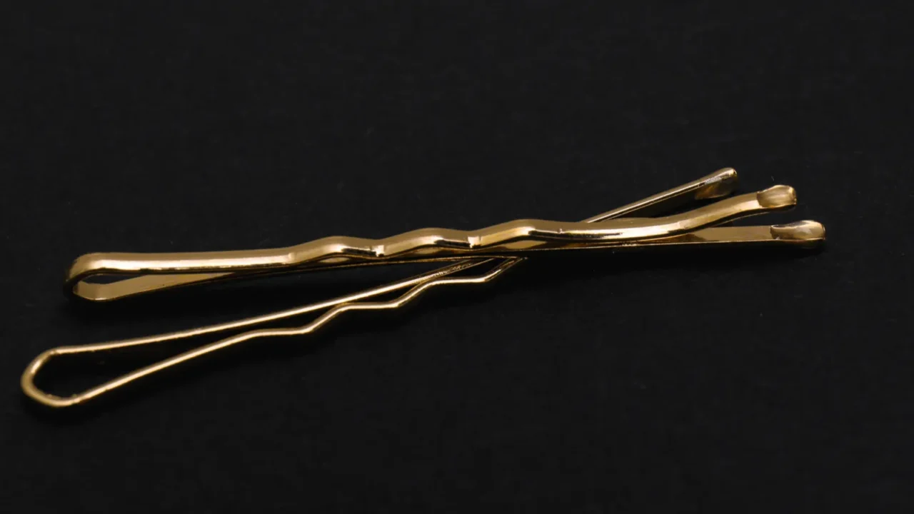 Gold invisible hair pins on black background