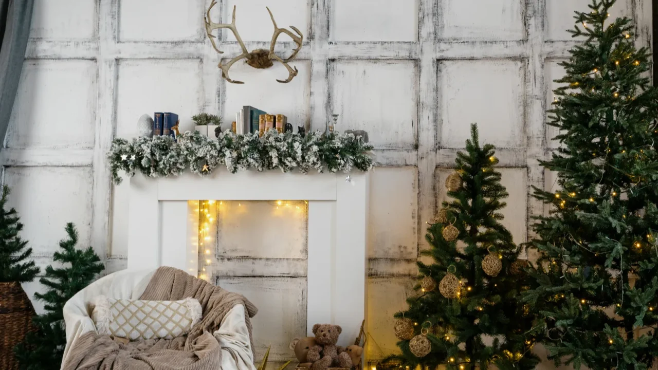 Panoramic view of cozy living room with garland lights on decorated new year tree, comfort armchair, fireplace, present boxes and traditional decor at home with winter style interior