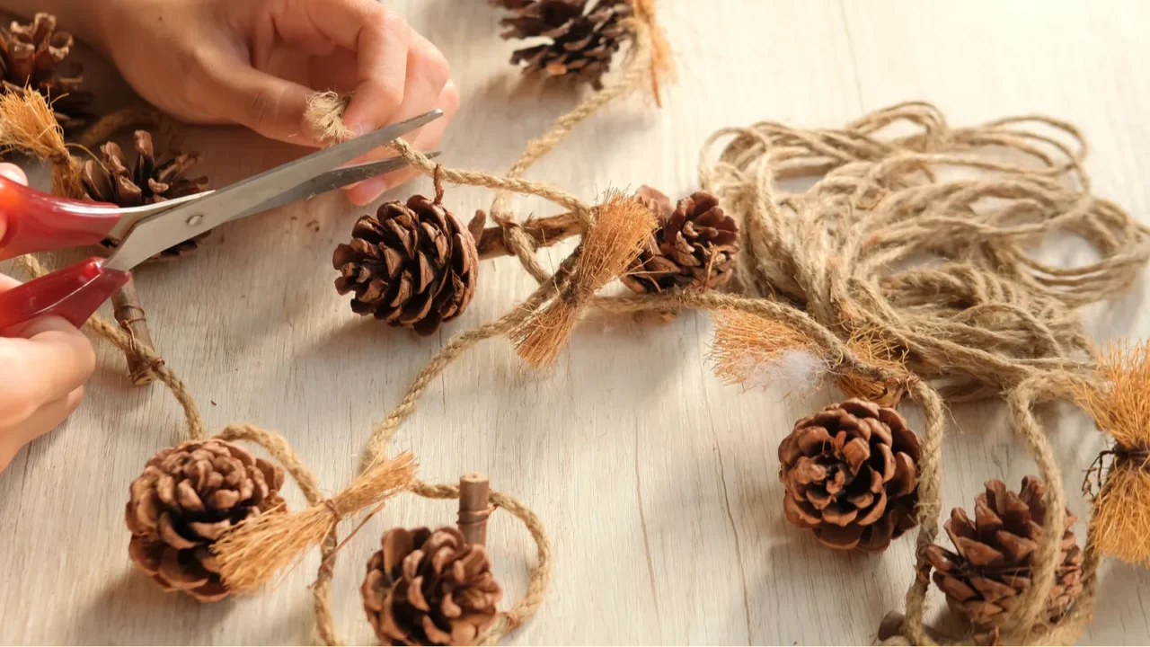 Part of a woman's hands making wall hangings from pinecones and jute rope