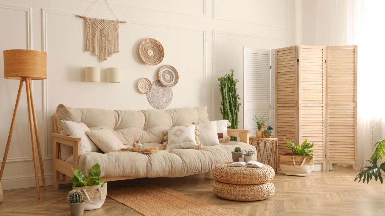 Boho Style living room with a beige sofa, wooden side tables, potted plants, and a woven wall hanging.