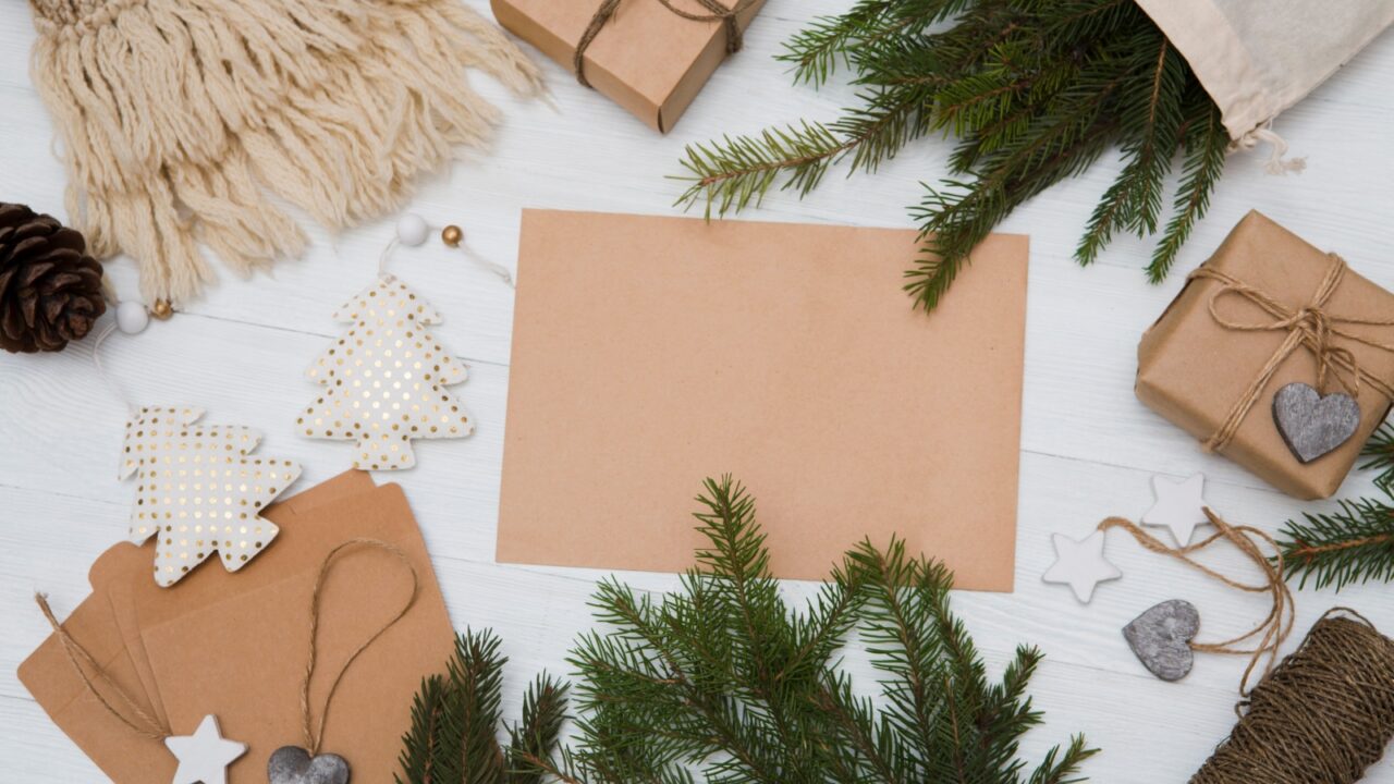 Eco-friendly decor items like Kraft paper, pinecones, eucalyptus branches, and handmade ornaments are placed on a white surface.