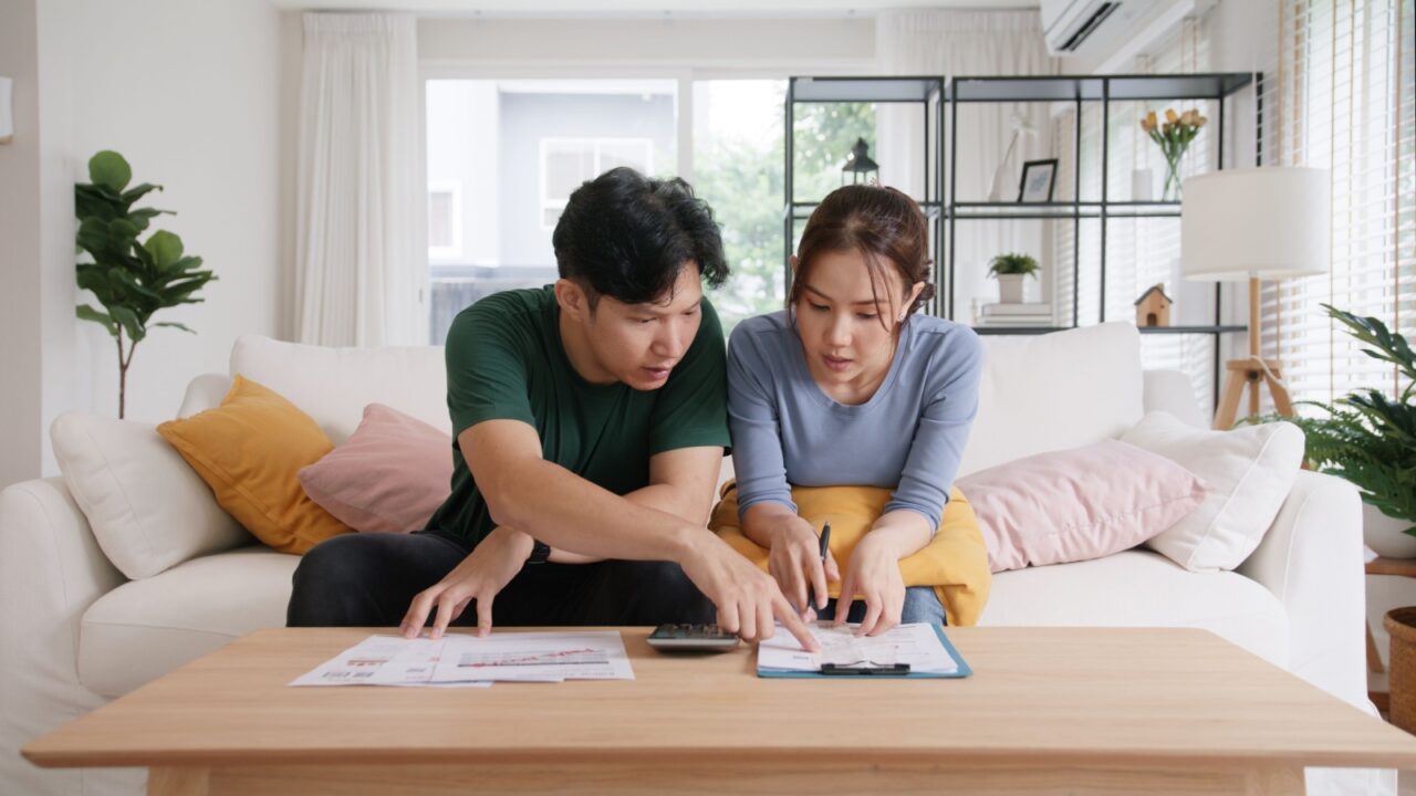 A couple sitting on the living room sofa, planning their monthly budget.