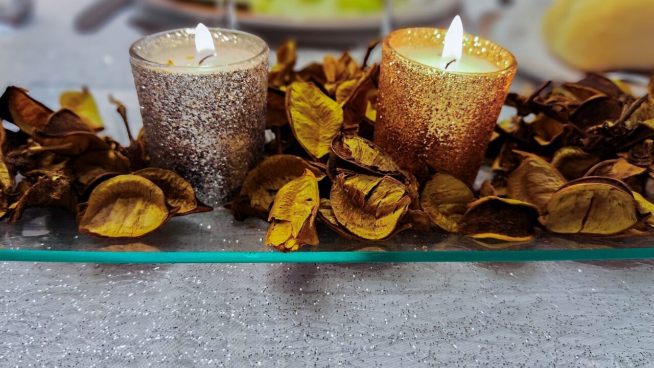 decorative centerpiece with gold and silver candles with dried leaves around it concept table decoration wedding or celebration