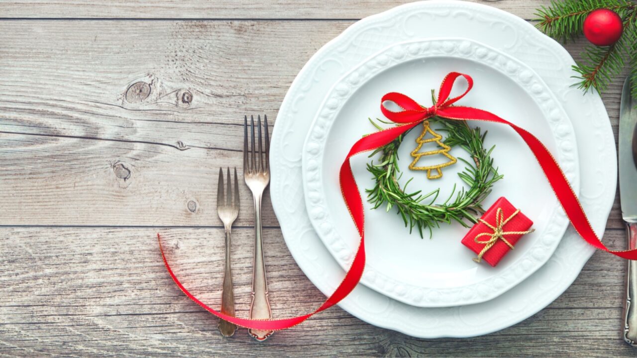 Served dinner table elegant arranged with Christmas decorations, rosemary wreath and gift box