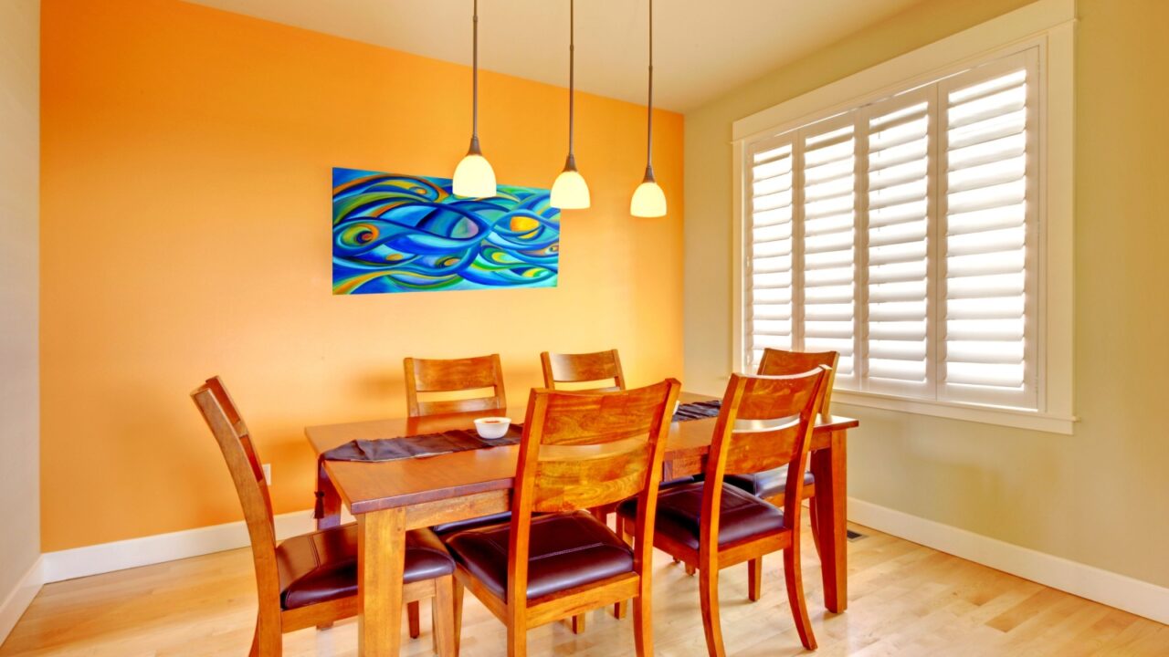 Orange dining room with wood table and hardwood floor.