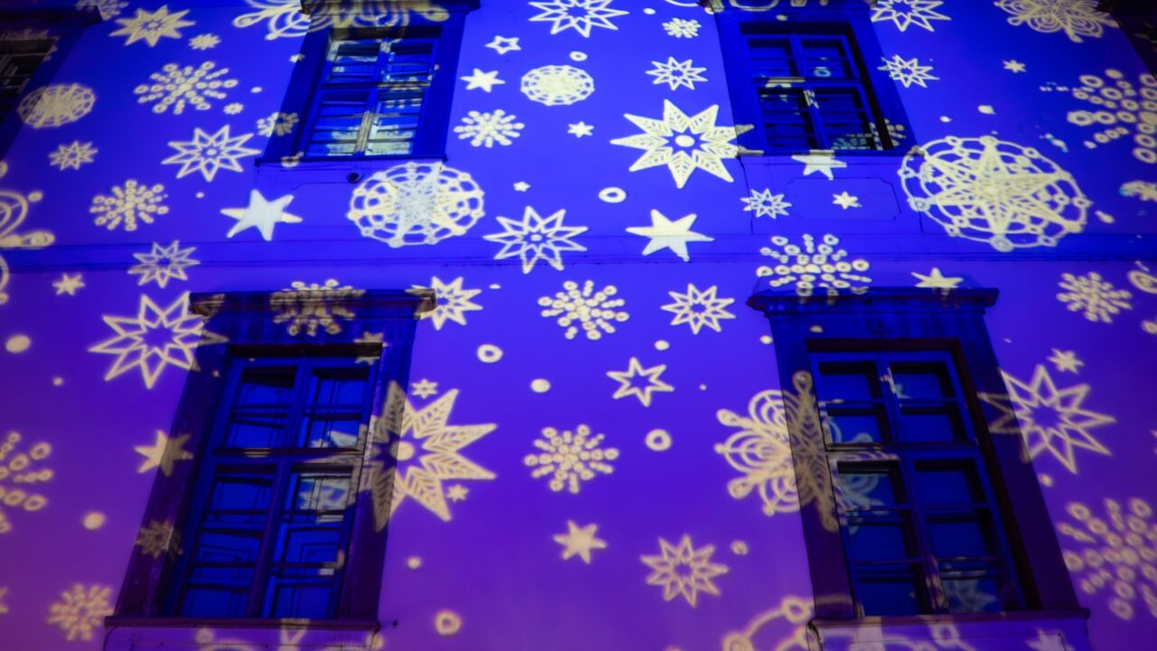 Blue and white Christmas pattern projected on a building. Christmas lights on a building