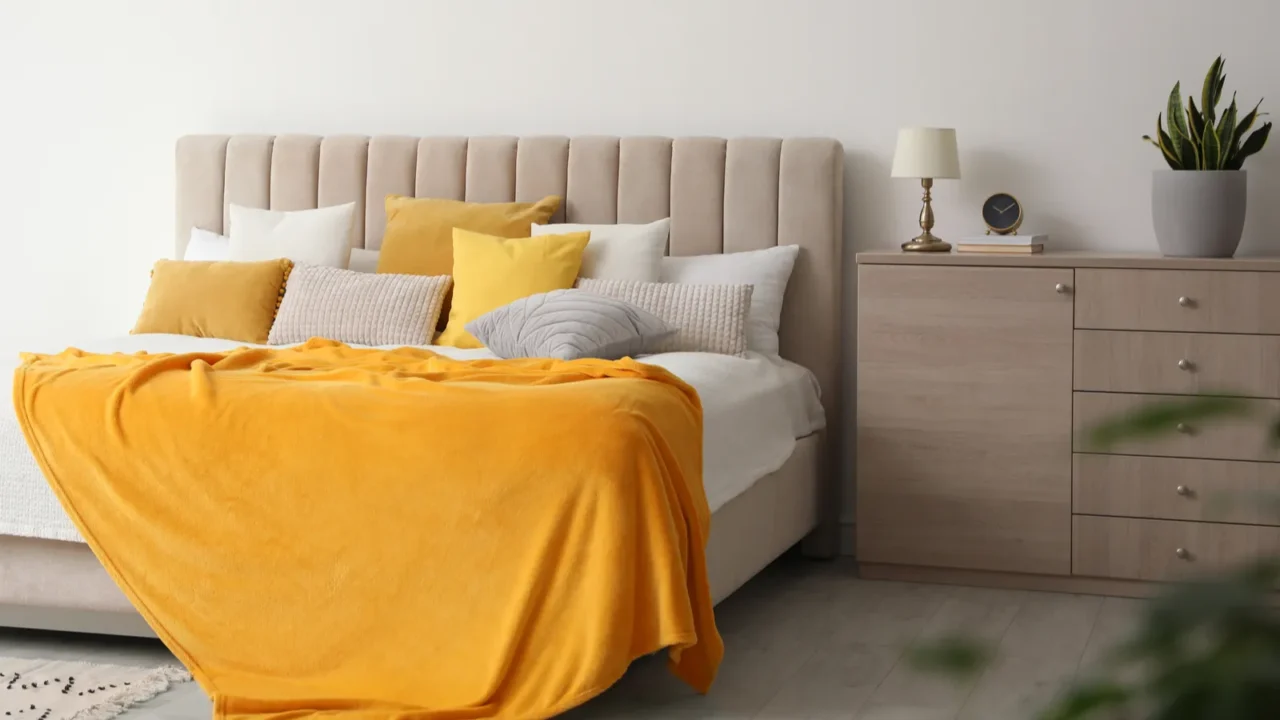 Stylish bedroom interior with soft yellow pillows and blanket