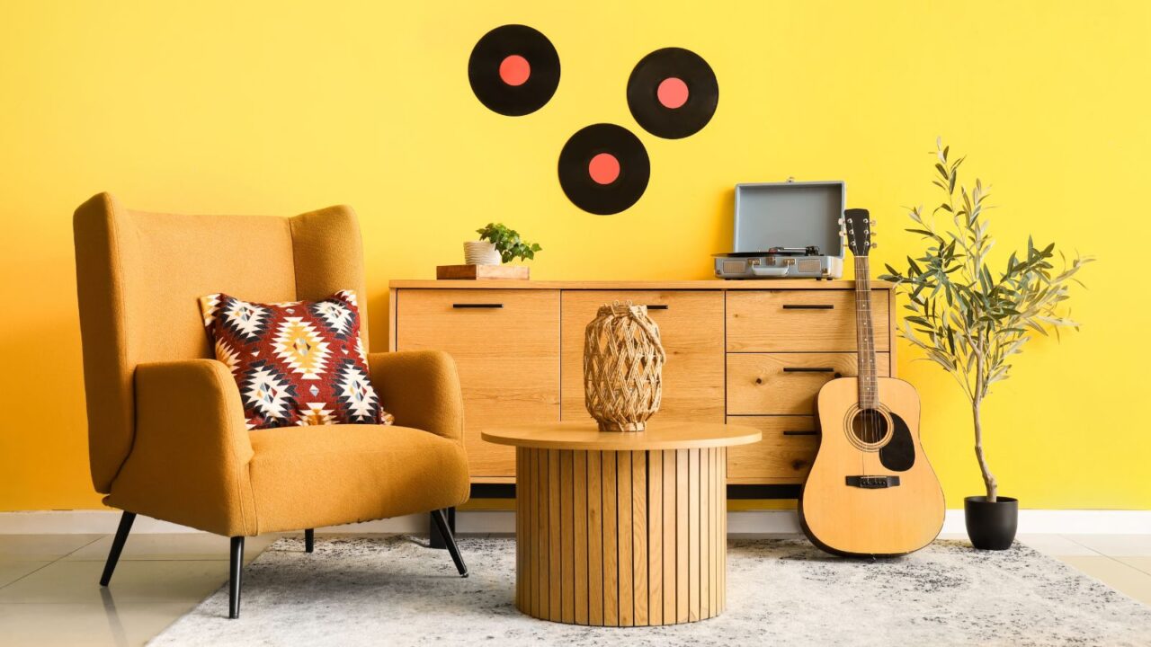 A beautiful yellow themed living room interior with a yellow sofa, guitar, a coffee table, houseplant, and a console table.