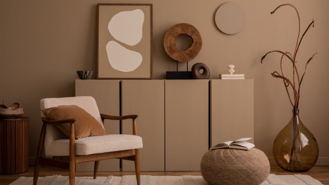 A cozy living room interior with a wooden chair, floor cushion, console table, vase, and decoration pieces.