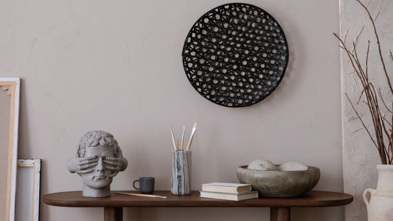 A wooden table with books, bowl, brush holder, and a sculpture.