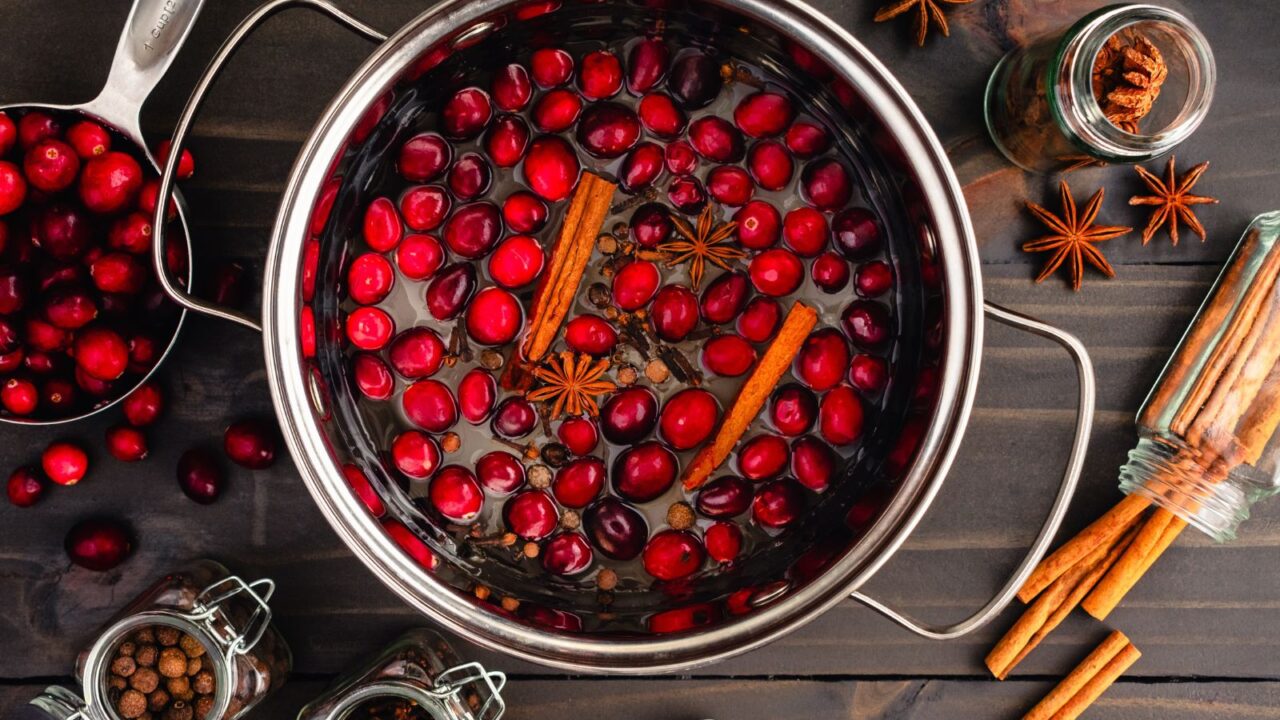 Spiced Cranberry in a small pan: Simmering sugar, cranberries, cinnamon sticks, star anise, cloves, and allspice berries.