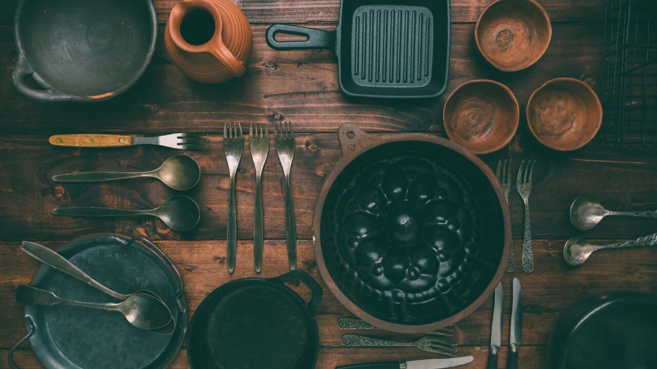 Kitchen utensils, cooking tools, and bowls on a wooden table.