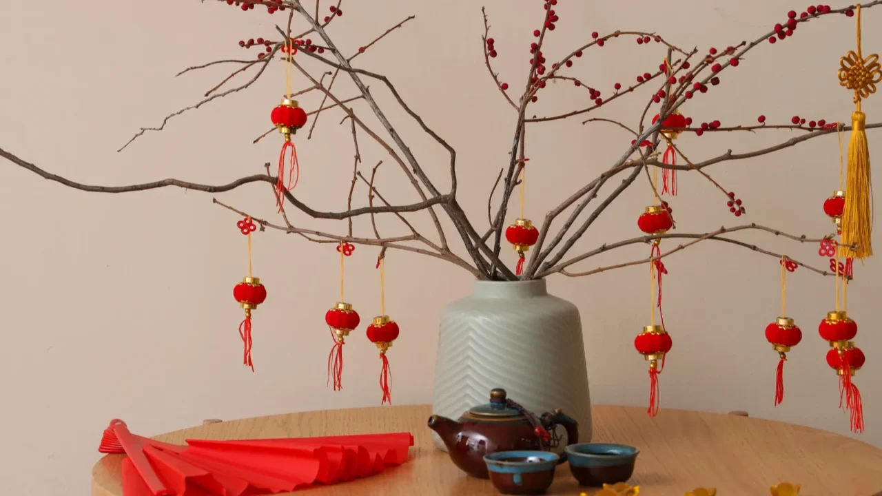 Vase with tree branches, Japanese symbols for New Year celebration and tea set on table in room