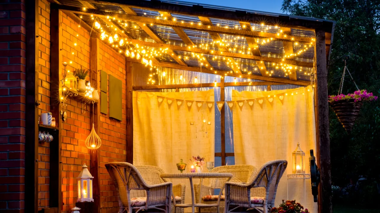 A beautiful terrace with fairy lights, chairs, table, buntings, and lanterns.