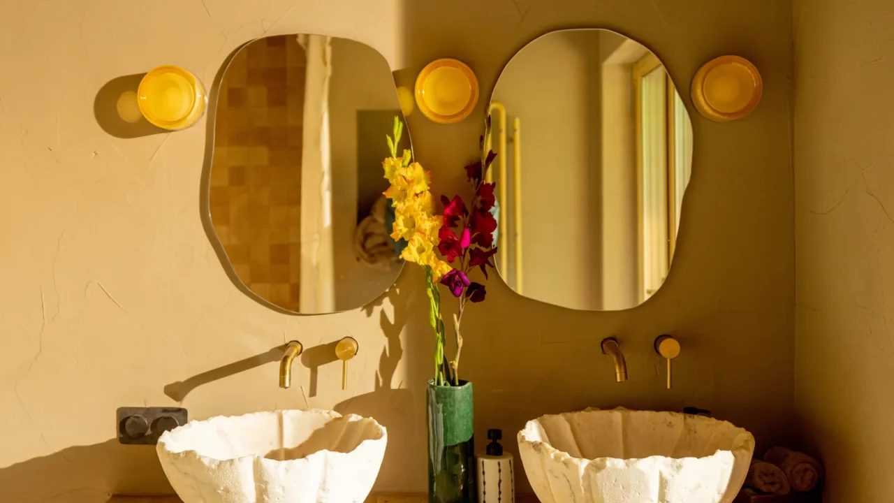 A bathroom vanity with two sculpted stone sinks and sculptural organic shaped mirrors.