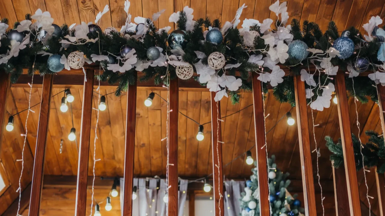 A beautifully adorned indoor space features blue lights and a garland with ornaments.