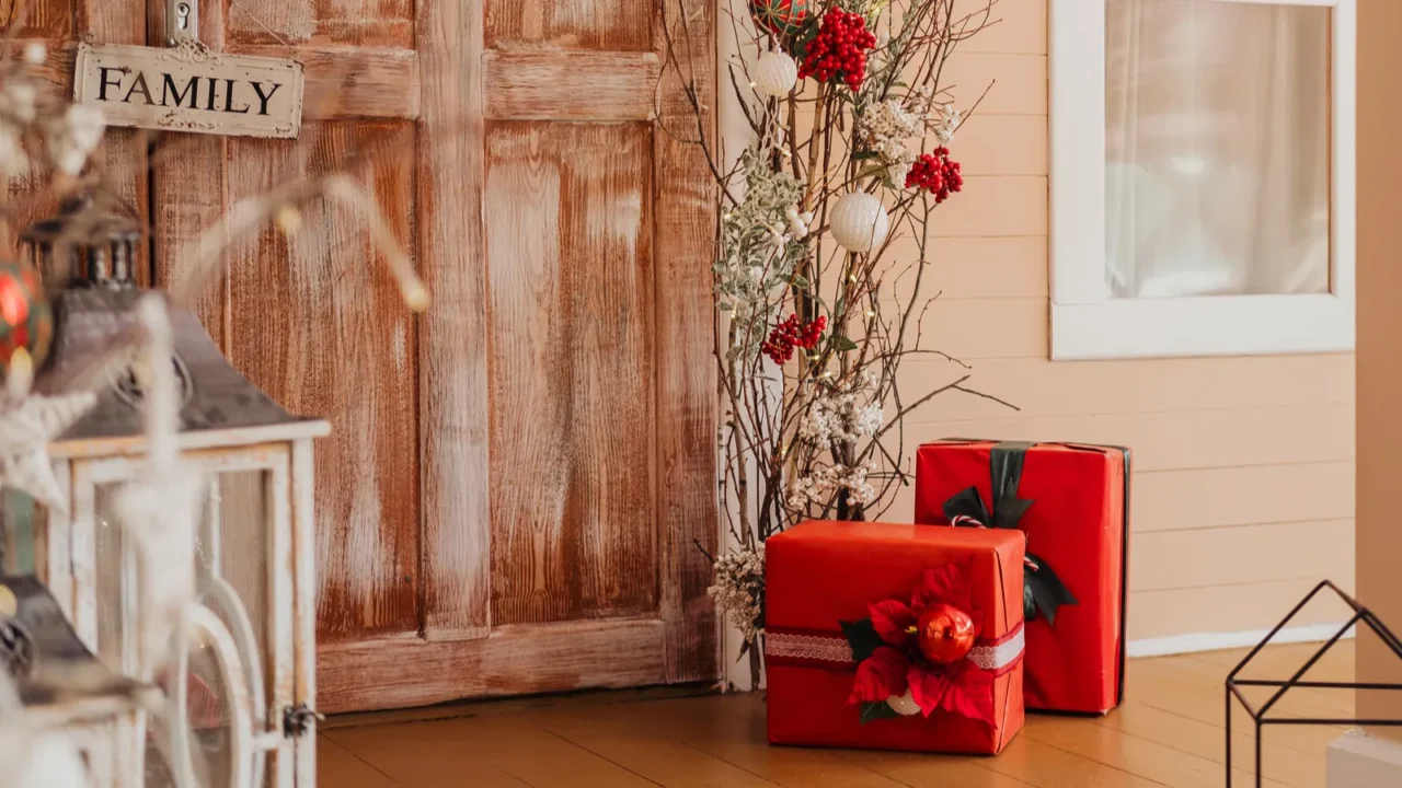 a cozy porch features a wooden door and festive red