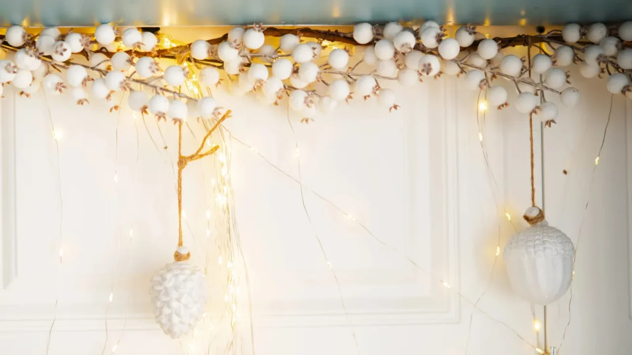 A cozy winter decoration adorns a white door. Lights hanging from the tree branch.