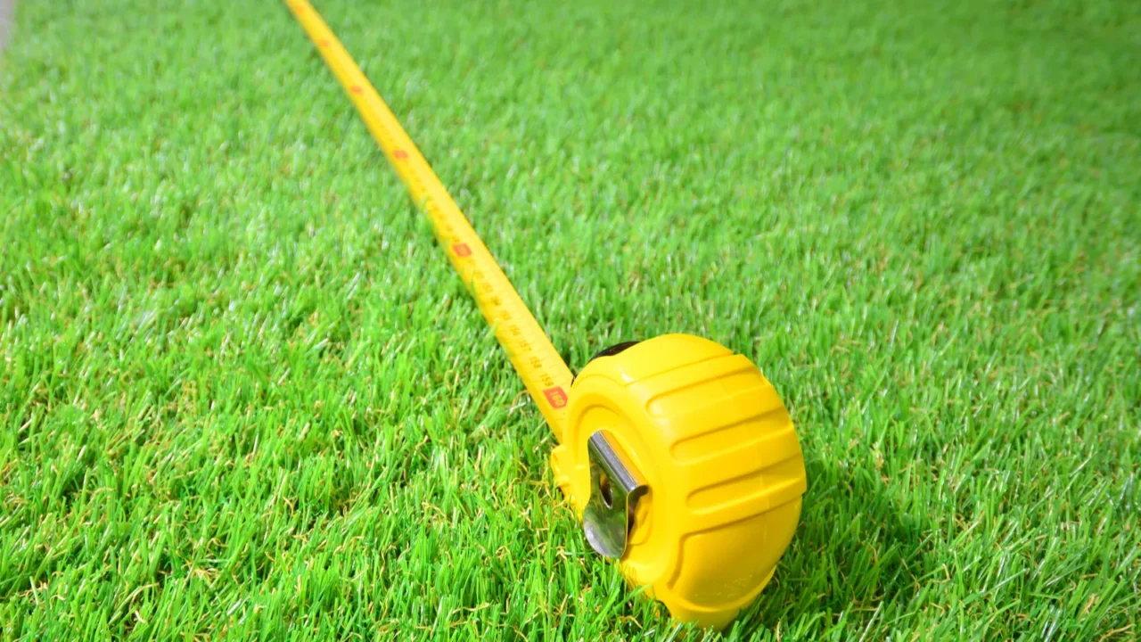 Artificial grass and measure tape lie on the laminate floor