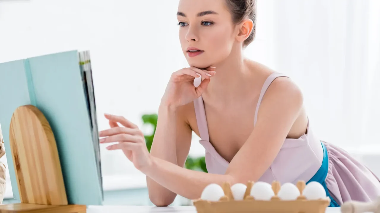 attractive girl reading recipe in cookbook with bakery ingredients around