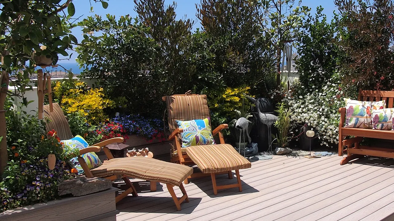 Beautiful blooming rooftop garden with comfortable seating chairs in city setting.