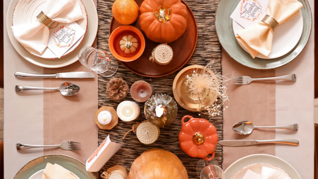 beautiful table setting with burning candles pumpkins and greeting cards