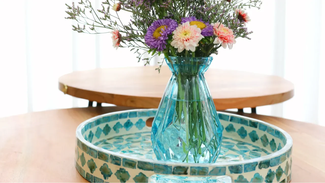 bouquet of colorful field flowers in the glass blue vase over wooden table