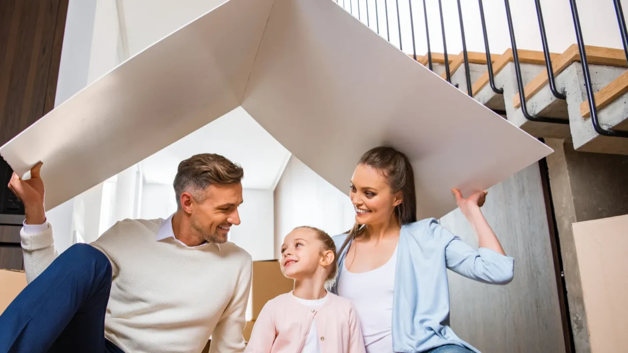 Cheerful family sitting under paper roof.