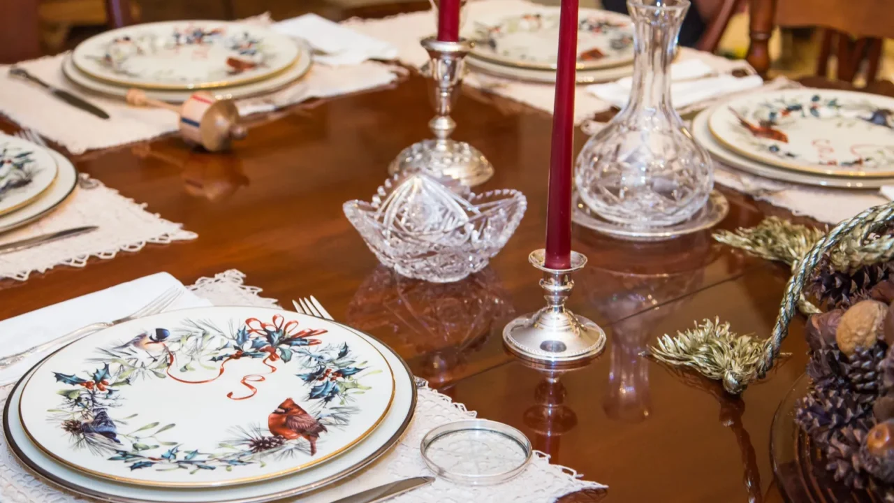 China plates floral print dinnerware on a formal dining table. Candle stands and a bowl on natural-inspired decorative elements.