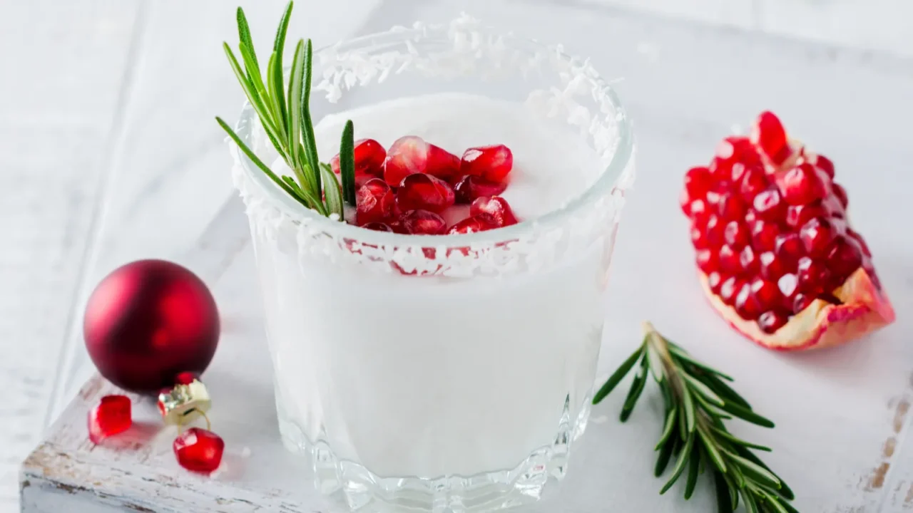 christmas coconut punch with pomegranate seeds and sprigs of rosemary