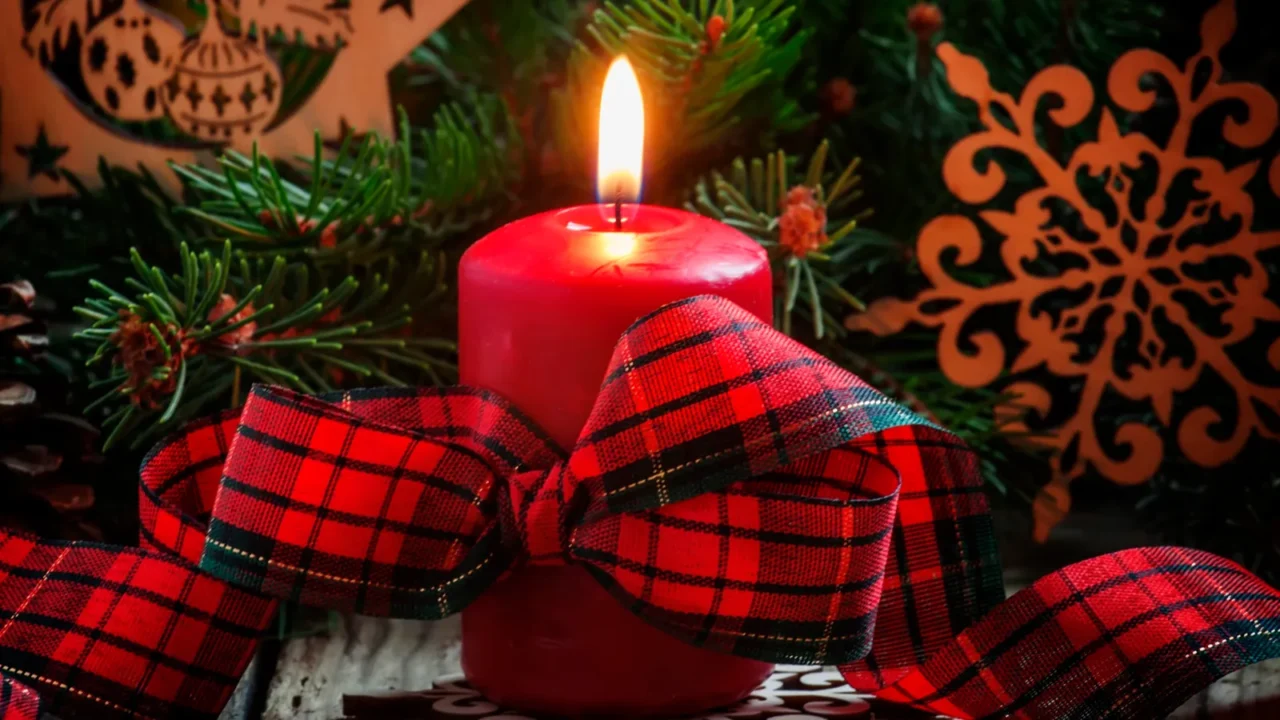 christmas composition with burning red candles tied with plaid ribbon