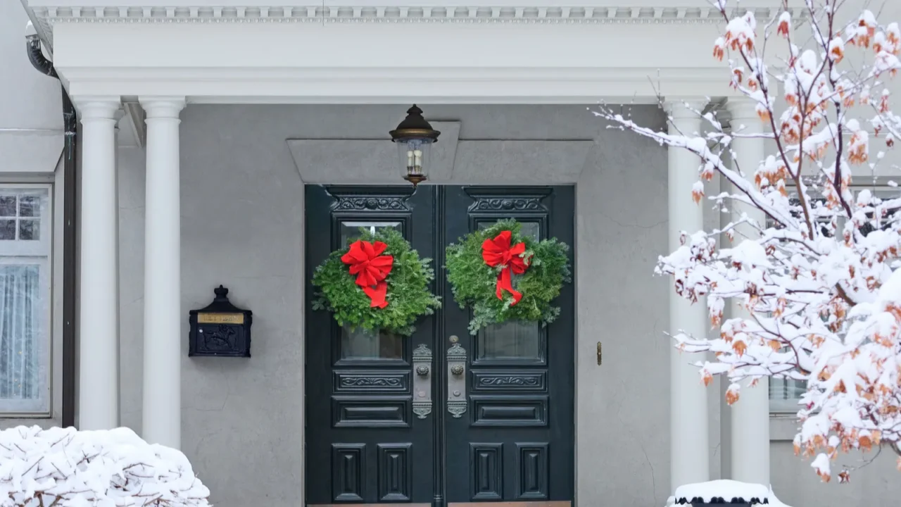 christmas wreath on double front door of snow covered house