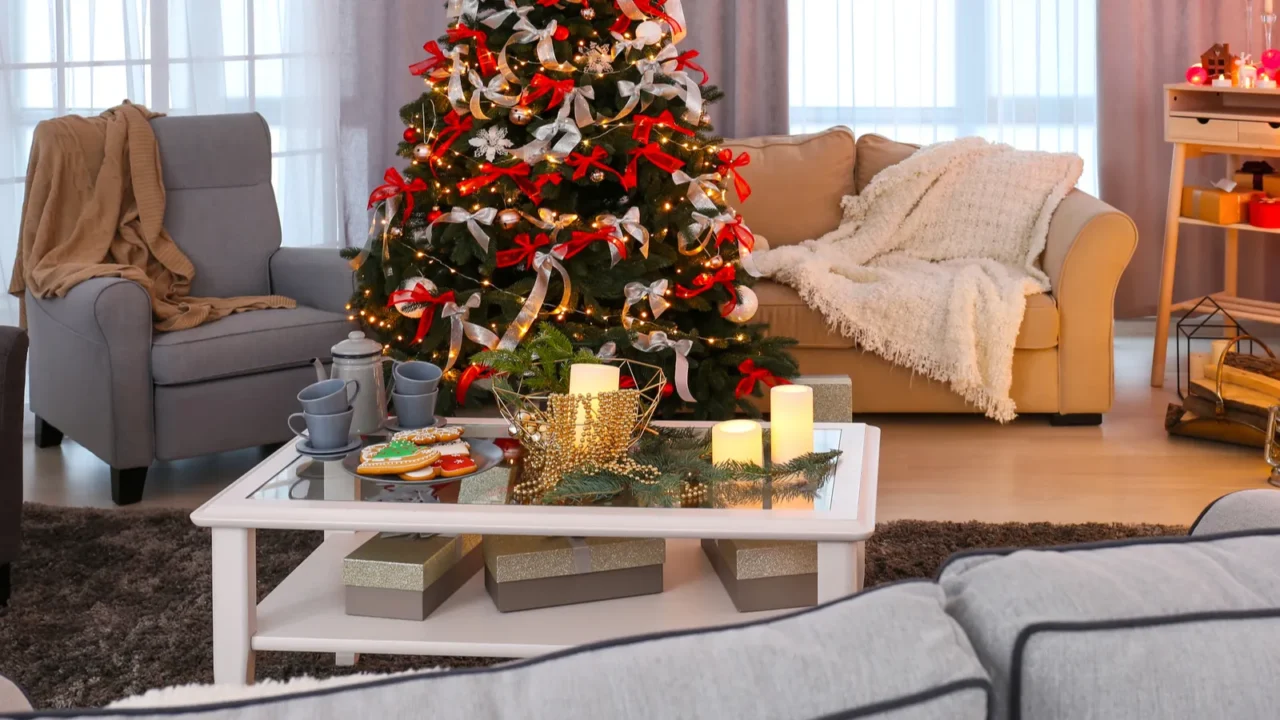 A cozy living room decorated for the holidays, featuring a Christmas tree with ornaments and lights, comfortable seating, a coffee table with festive treats, and candles.