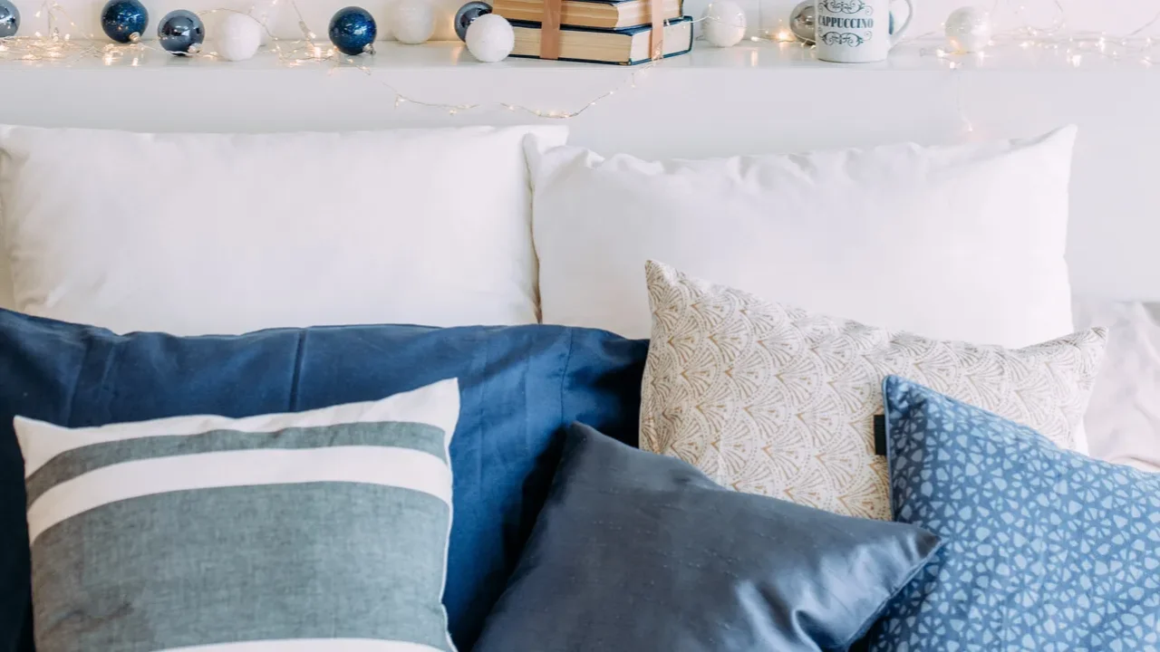 Elegant Christmas interior. White sofa and blue pillows. White and blue baubles, books, and mug in the background.