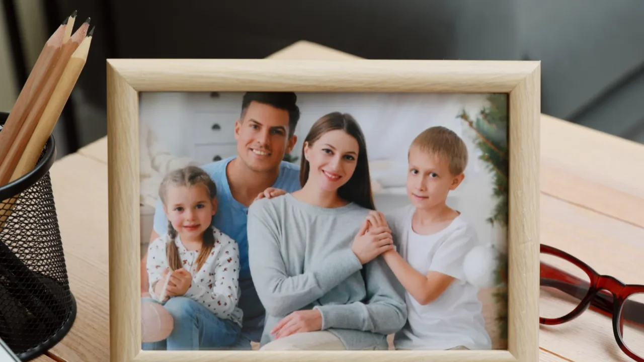 framed family photo near laptop on wooden table in office