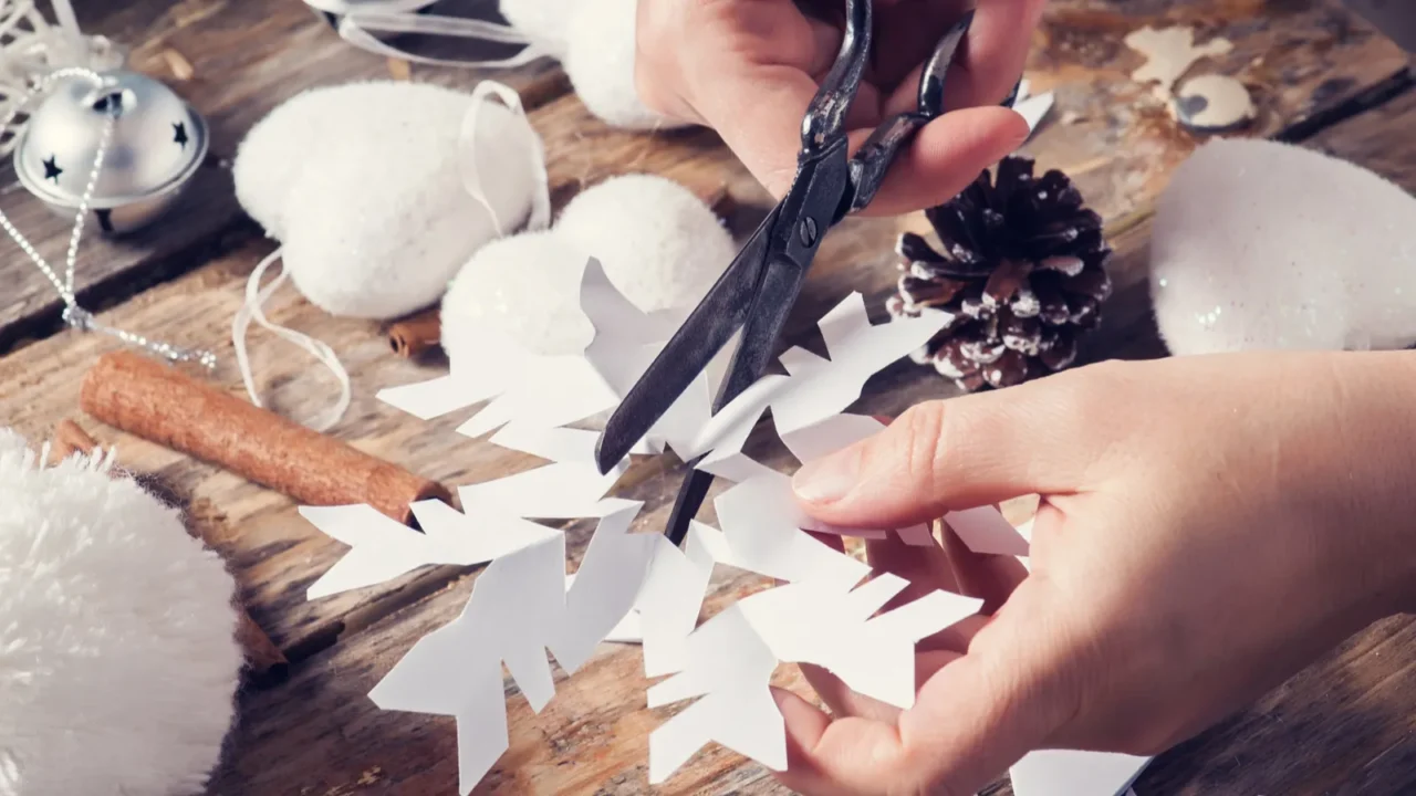 girl sitting at her desk cutting snowflake for christmas decor