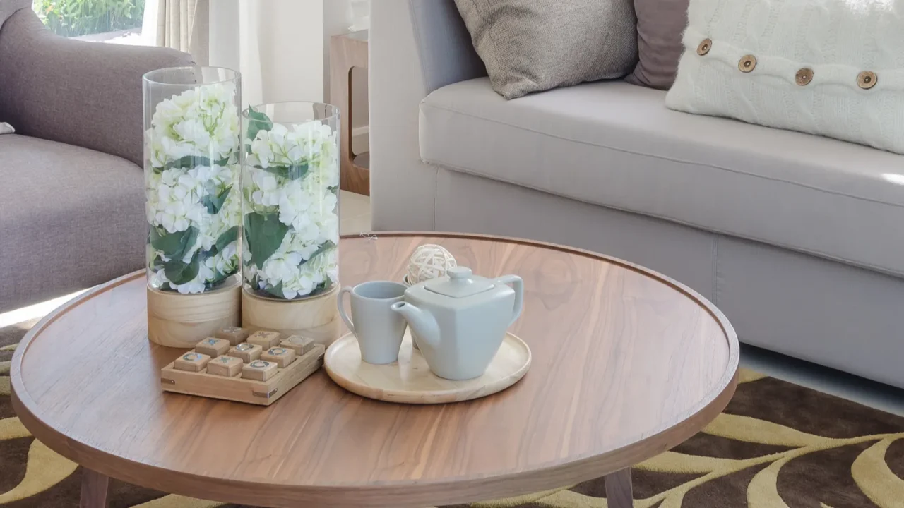 glass vase of plants and tea cup set on wooden