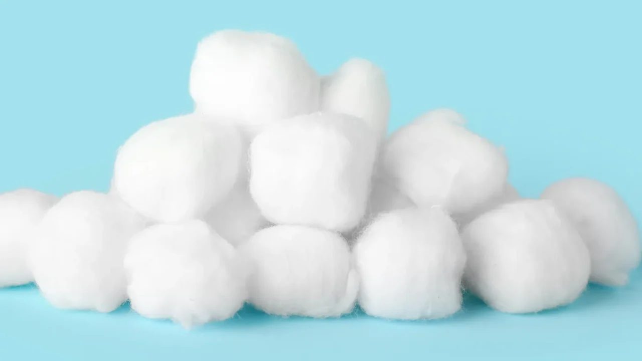 heap of cotton balls on color background