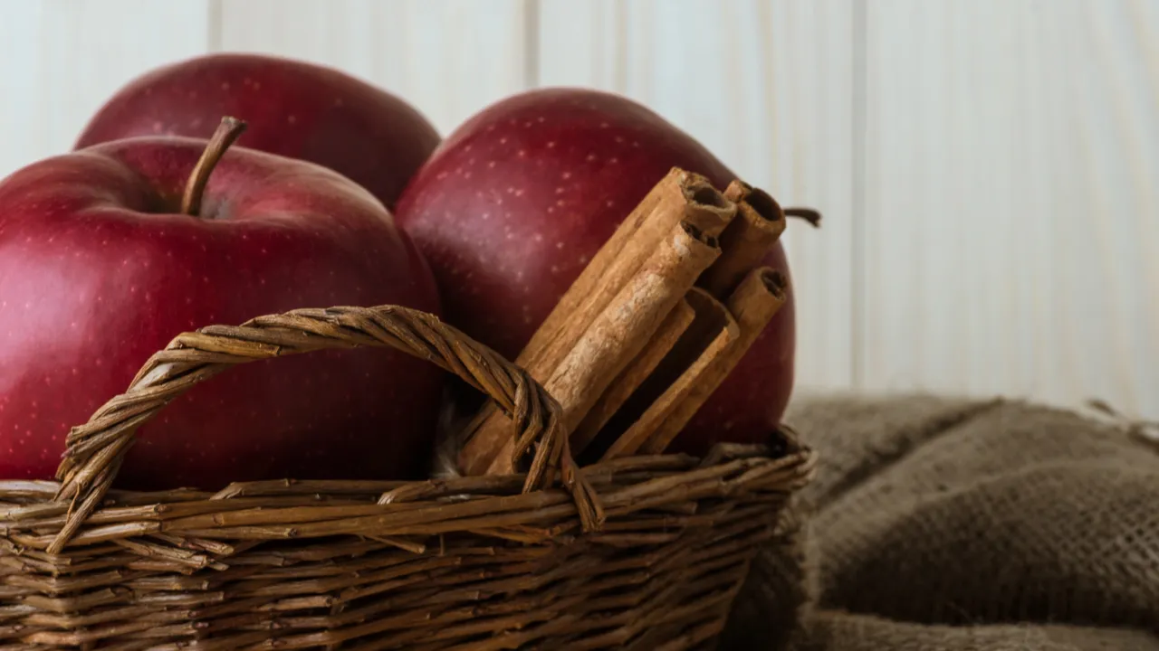 Apples and cinnamon sticks in a basket.