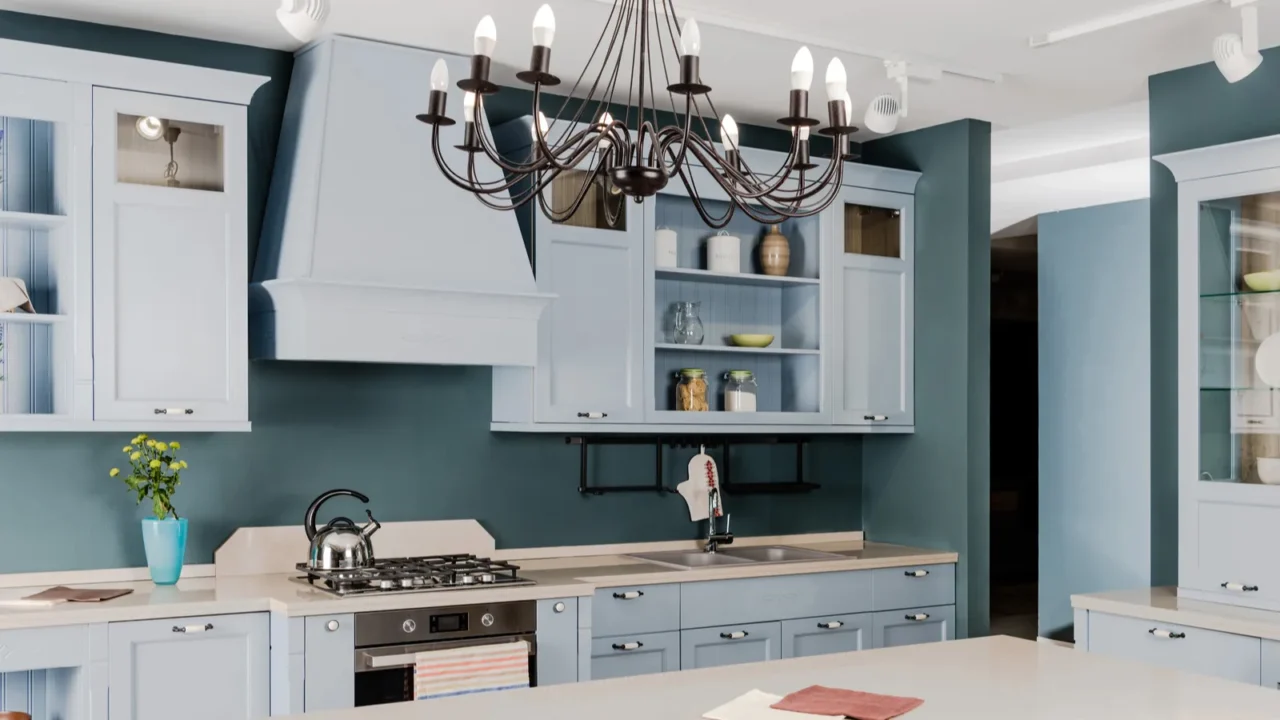 Interior of modern light kitchen in shades of blue with white wooden countertops.