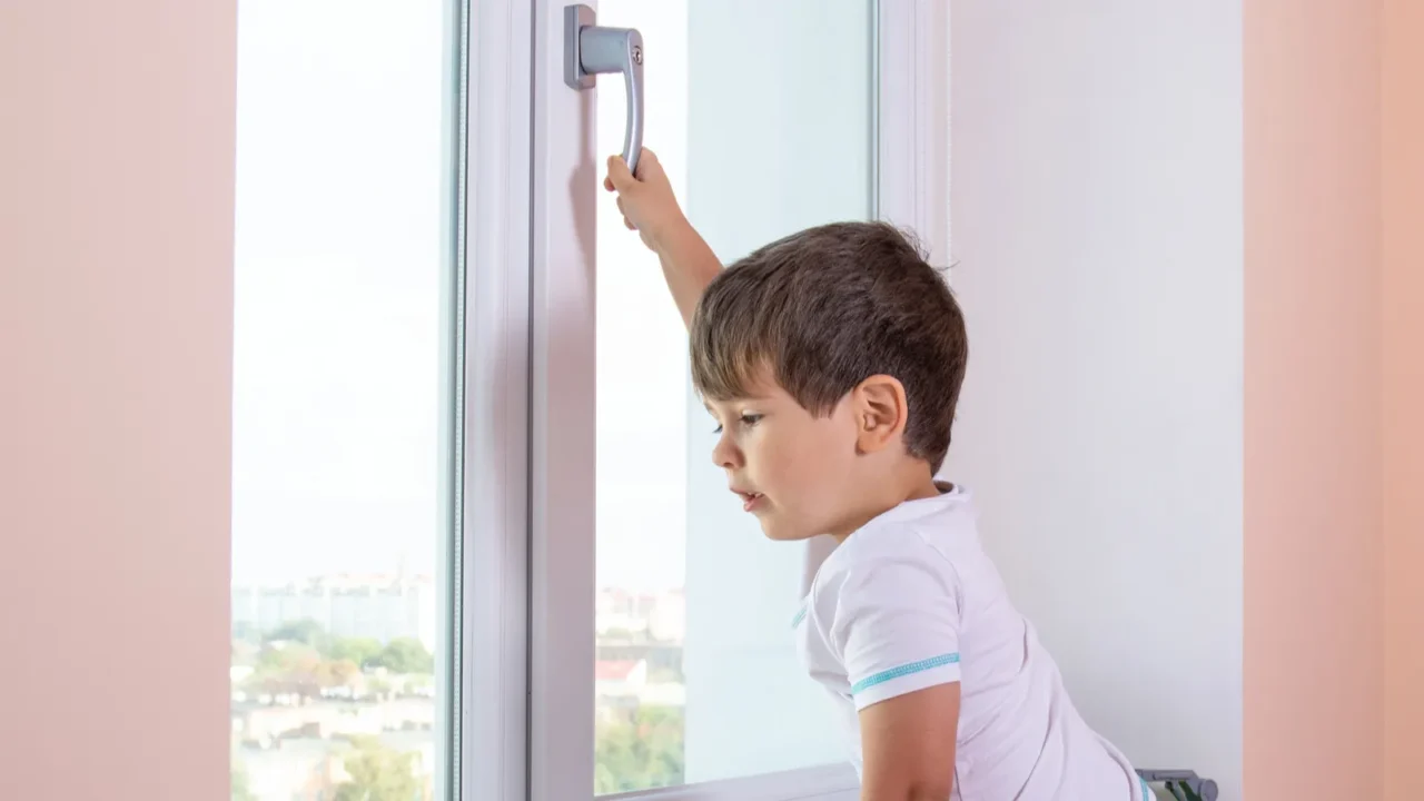 kid trying to open the window pulling its handle child