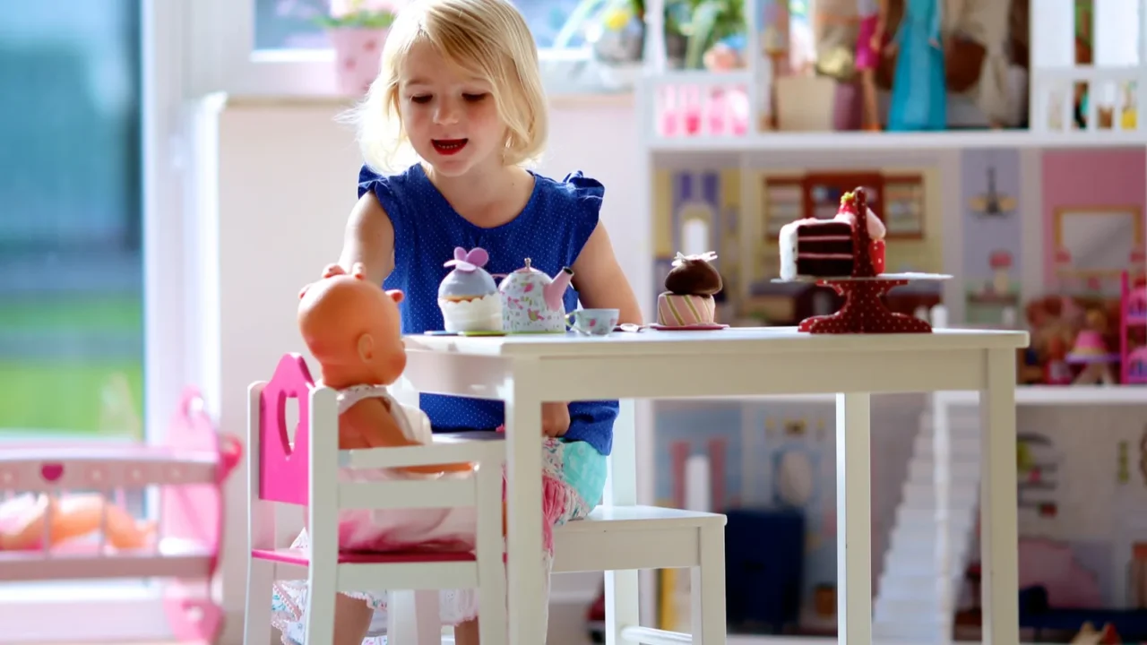 little girl having playing tea party with dolls