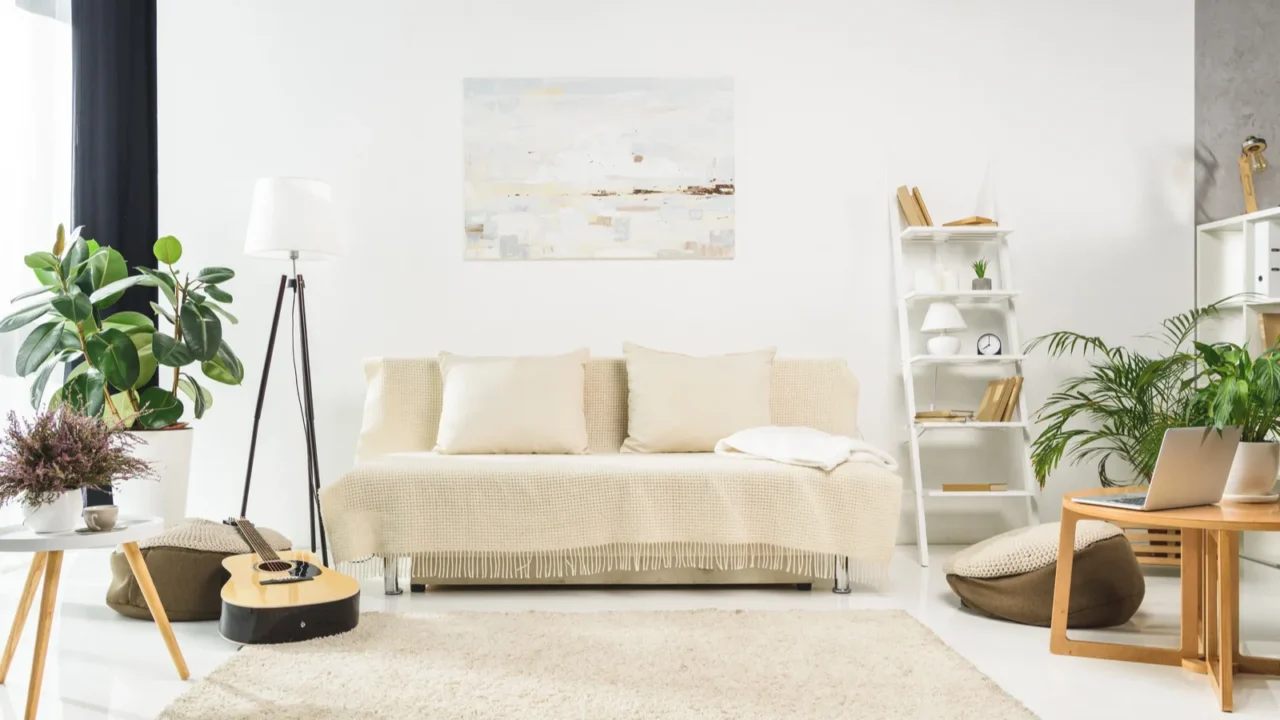 White living room interior. A well-lit room with plants and a guitar lying on the rug.