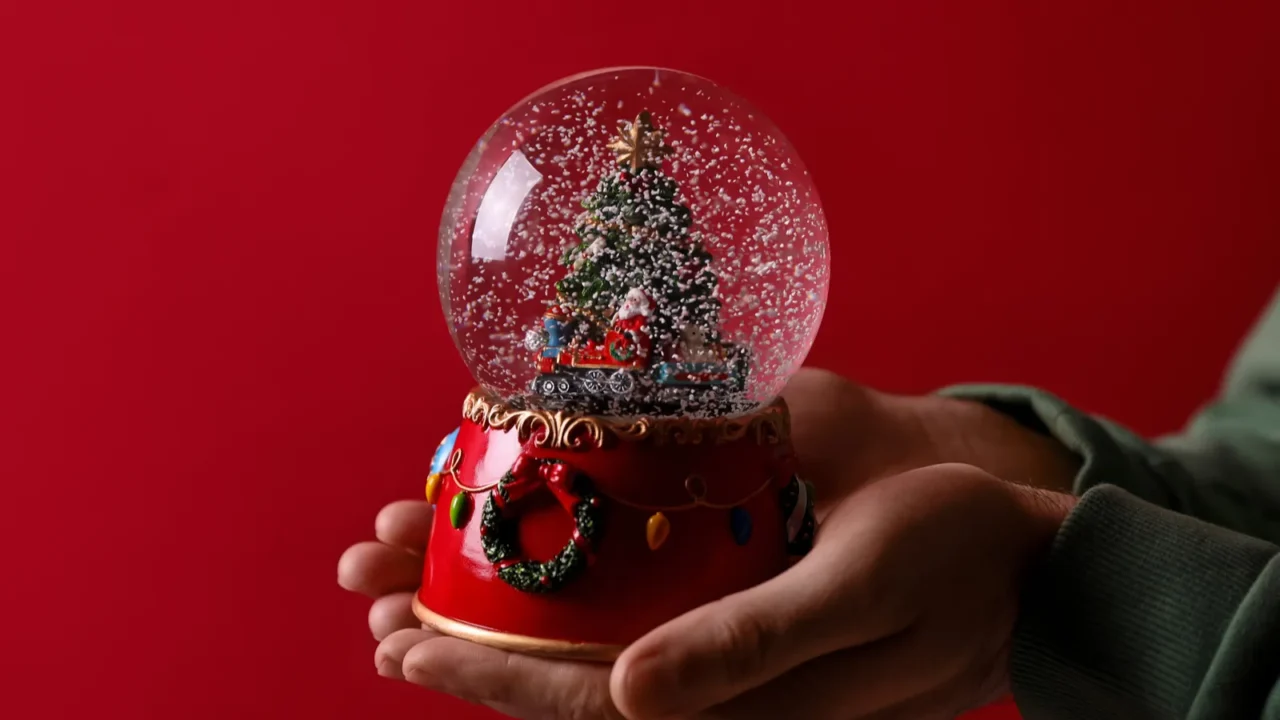 man holding snow globe on red background closeup