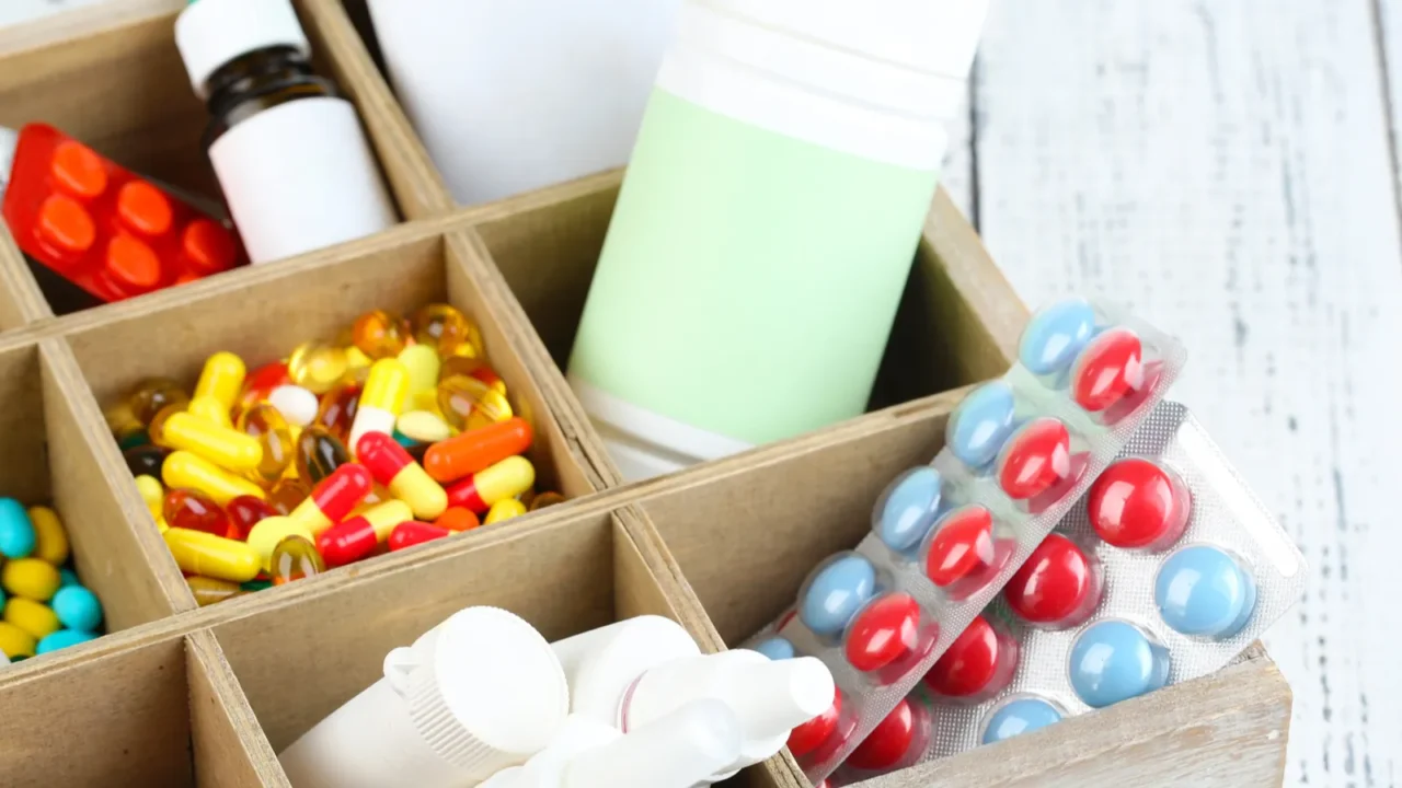 medical pills ampules in wooden box on color background